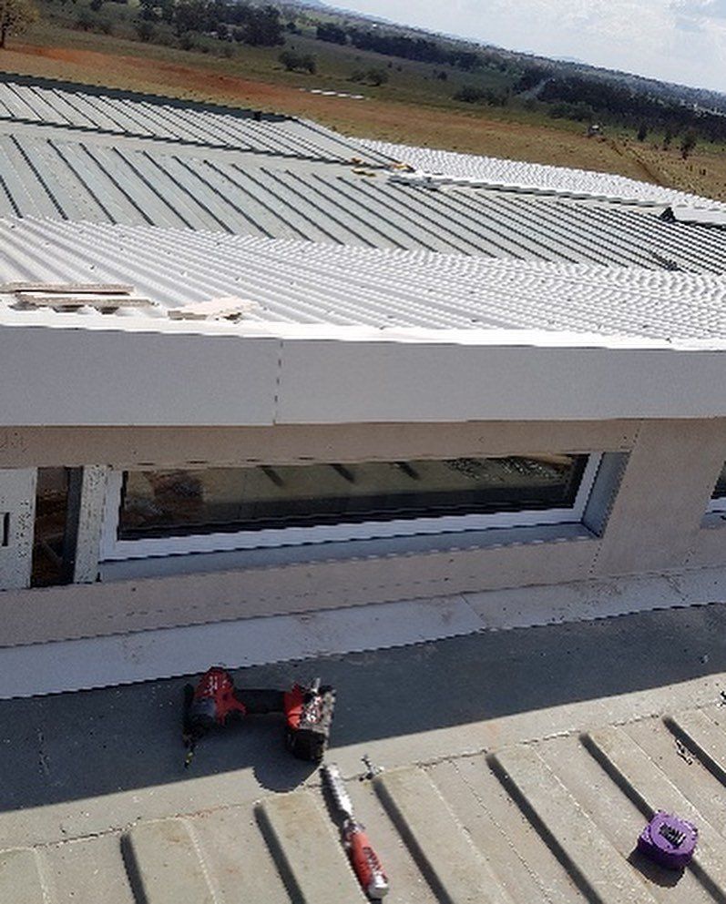 Close-up of a building's roof with a skylight and tools on the metal surface.