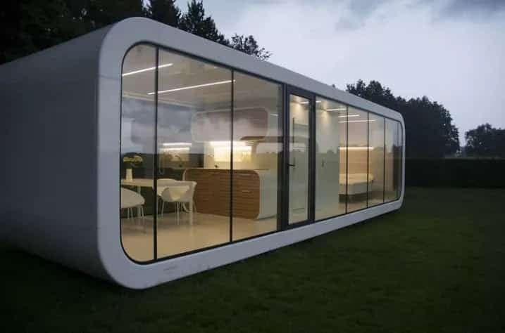 Modern, white, rectangular house with rounded corners and large glass windows; set in a grassy yard.