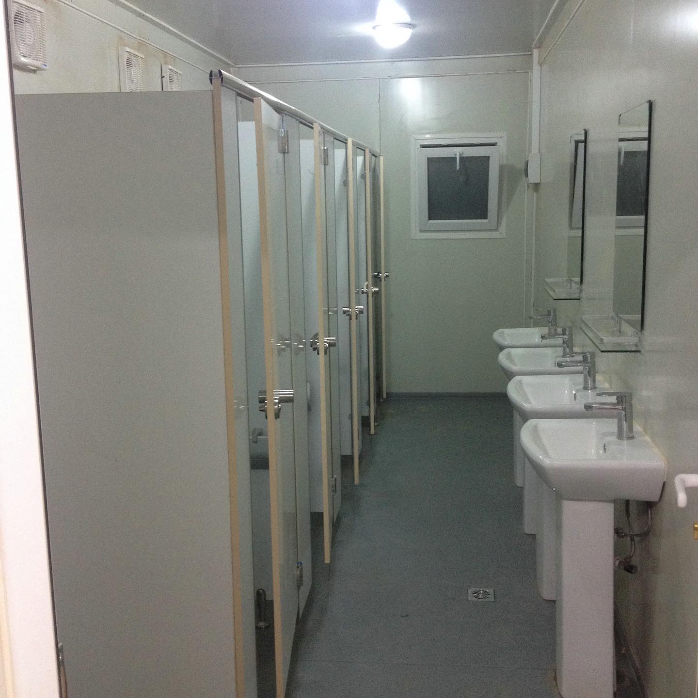 Public restroom with white stalls, sinks, and mirrors.