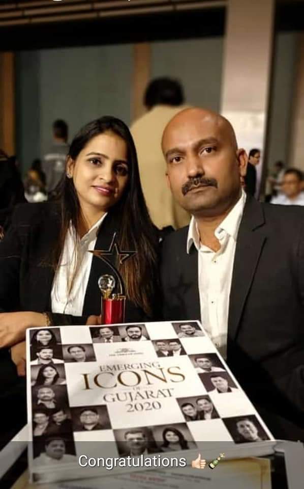 Woman and man posing with a trophy and a book titled