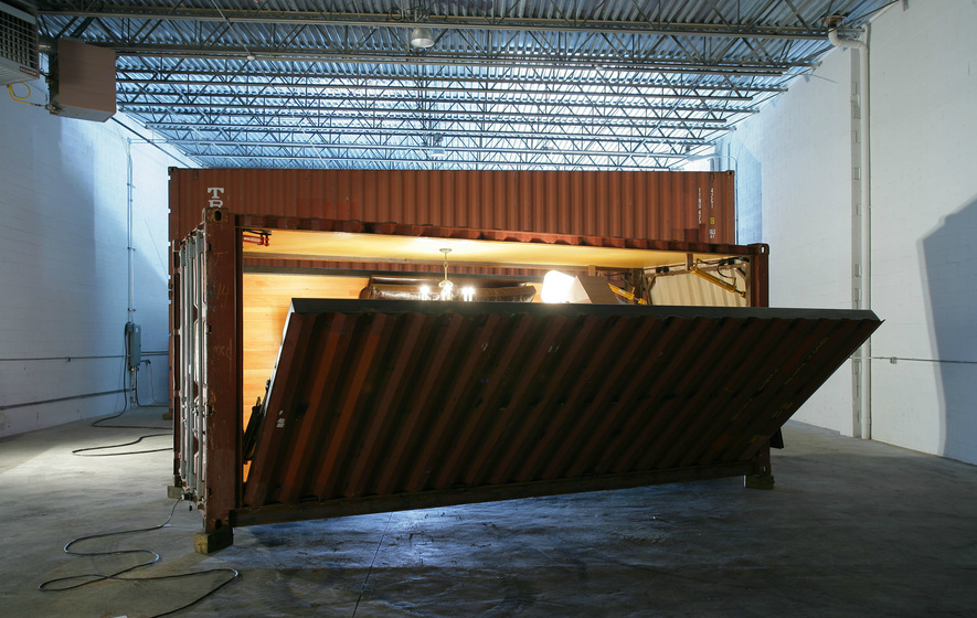 Shipping container with one door open, revealing interior. Inside, a spotlight shines.