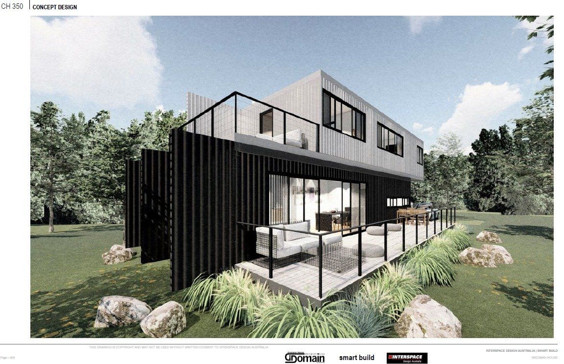 Modern two-story house with black siding, a balcony, and a patio, nestled in a grassy landscape with trees and large rocks.
