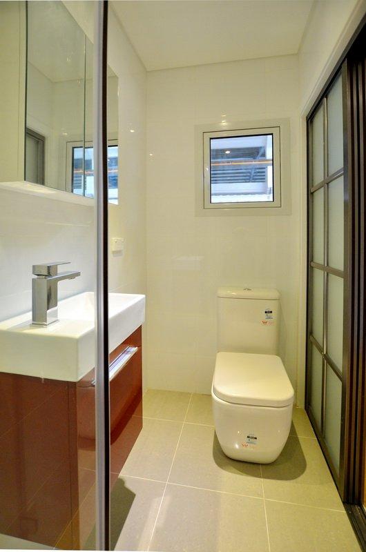 Small bathroom with white walls, a toilet, a vanity, and a window.
