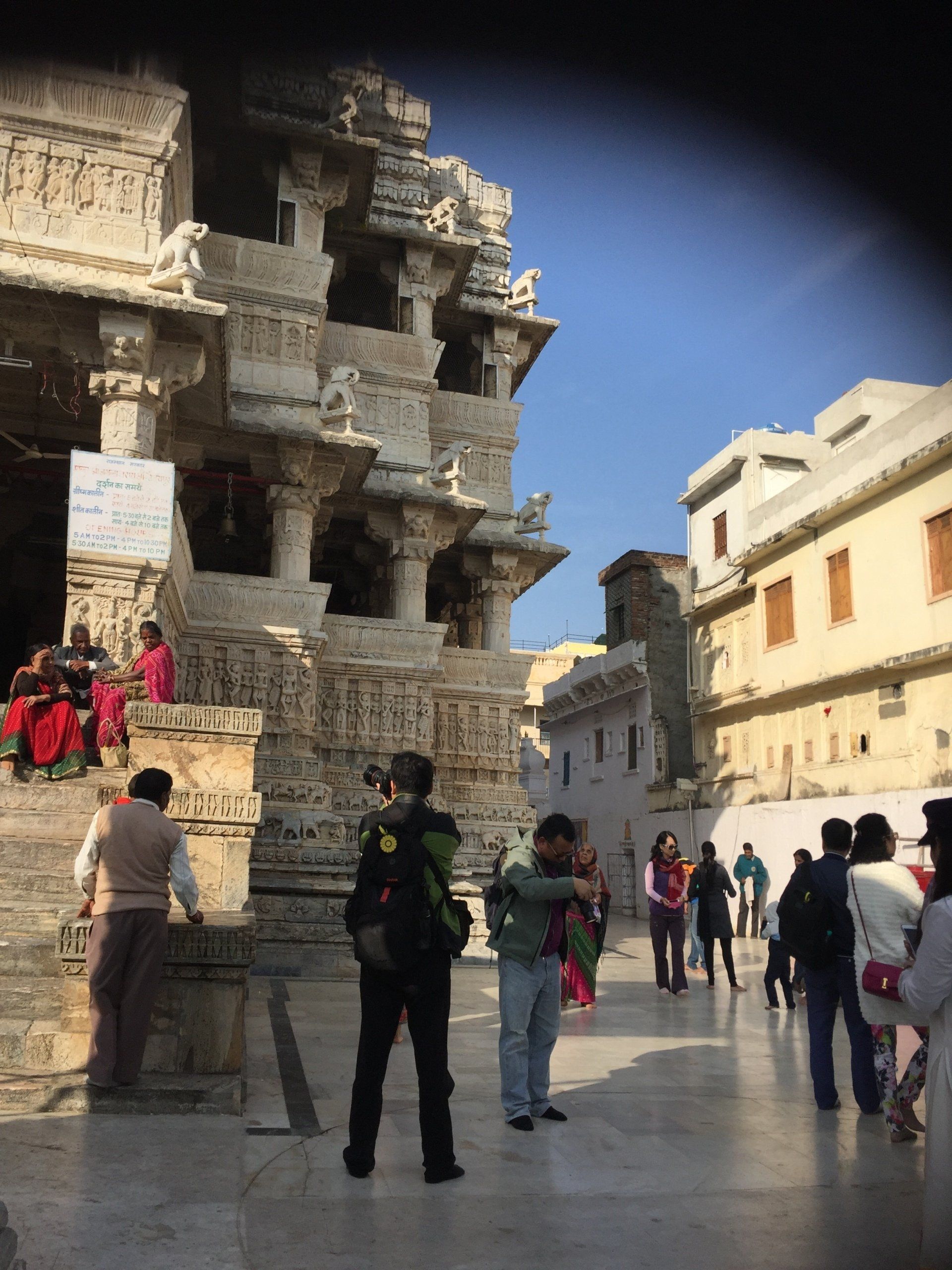 Ornate white temple exterior with tourists milling about; sunny day.