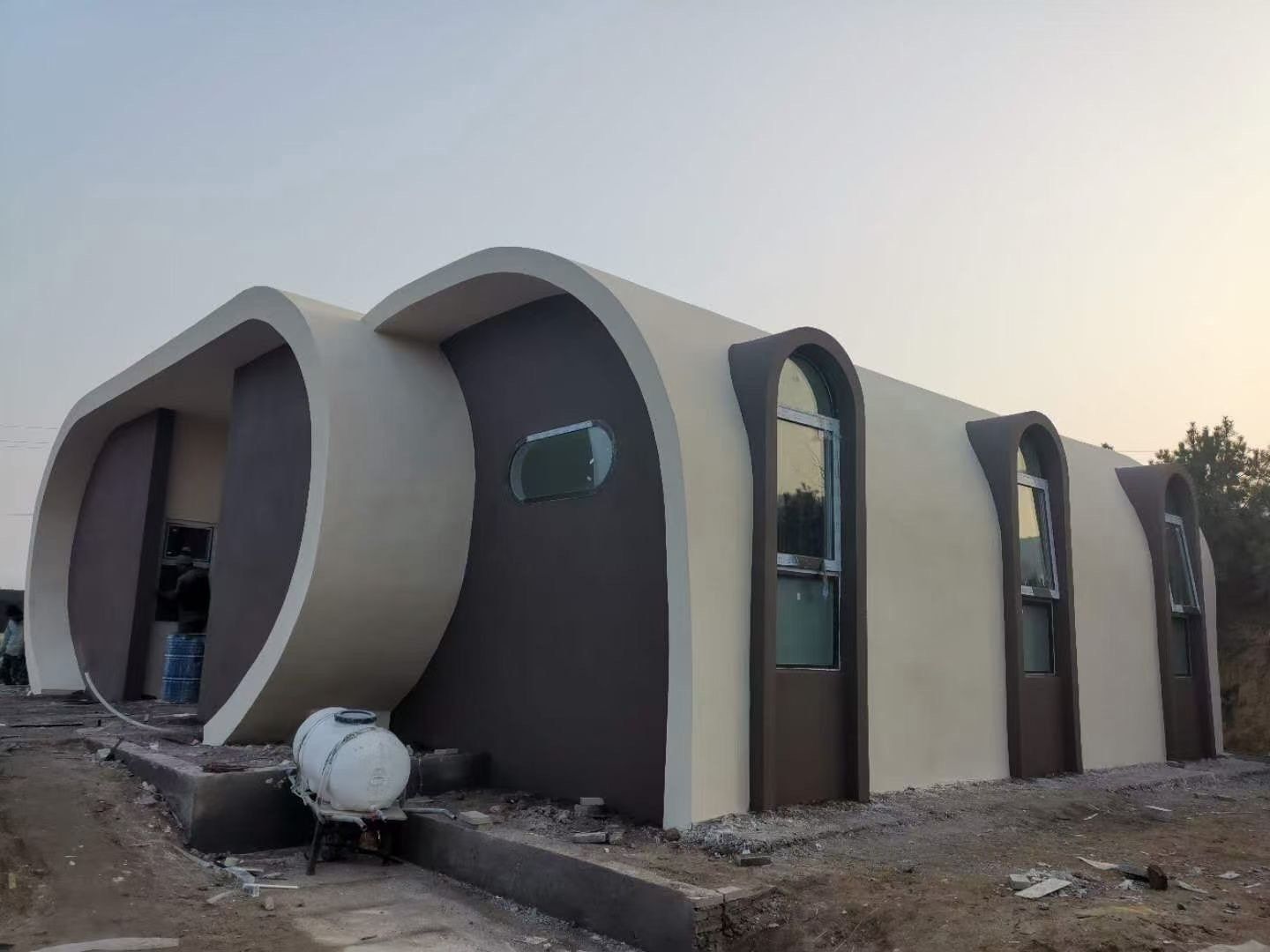 Beige and brown modern, pod-shaped building under construction with arched windows and curved elements.