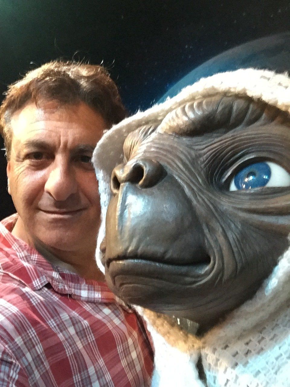 Man poses for selfie with E.T. alien puppet wearing a winter cap.