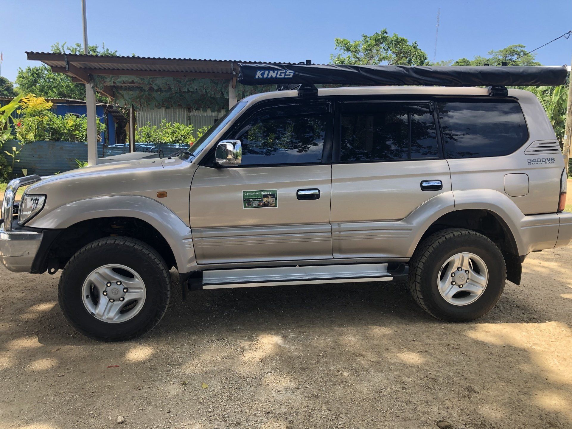 Tan Toyota Land Cruiser Prado with a roof rack parked outdoors.