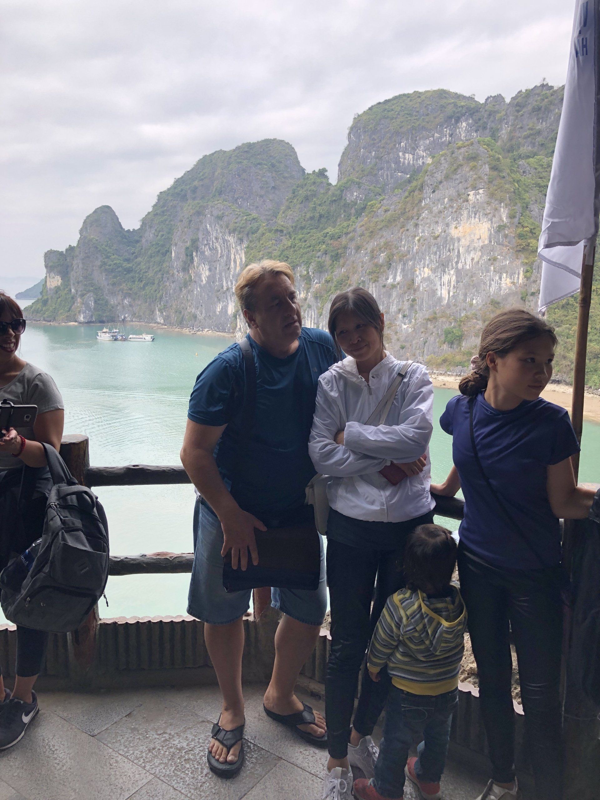 Family on a boat, posing in front of a scenic seascape with rock formations and water.