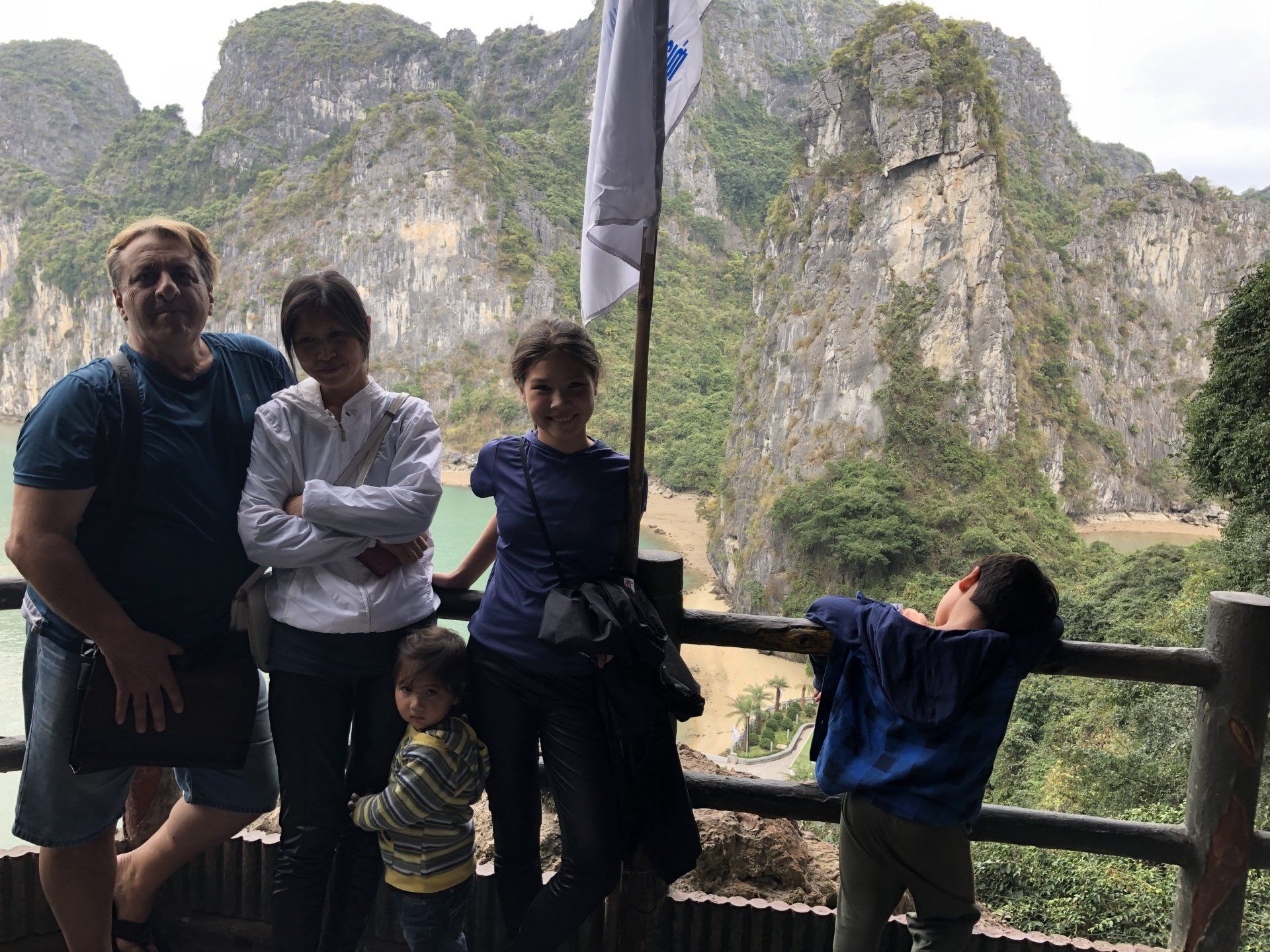 Family poses on a wooden deck overlooking a mountainous landscape and body of water.