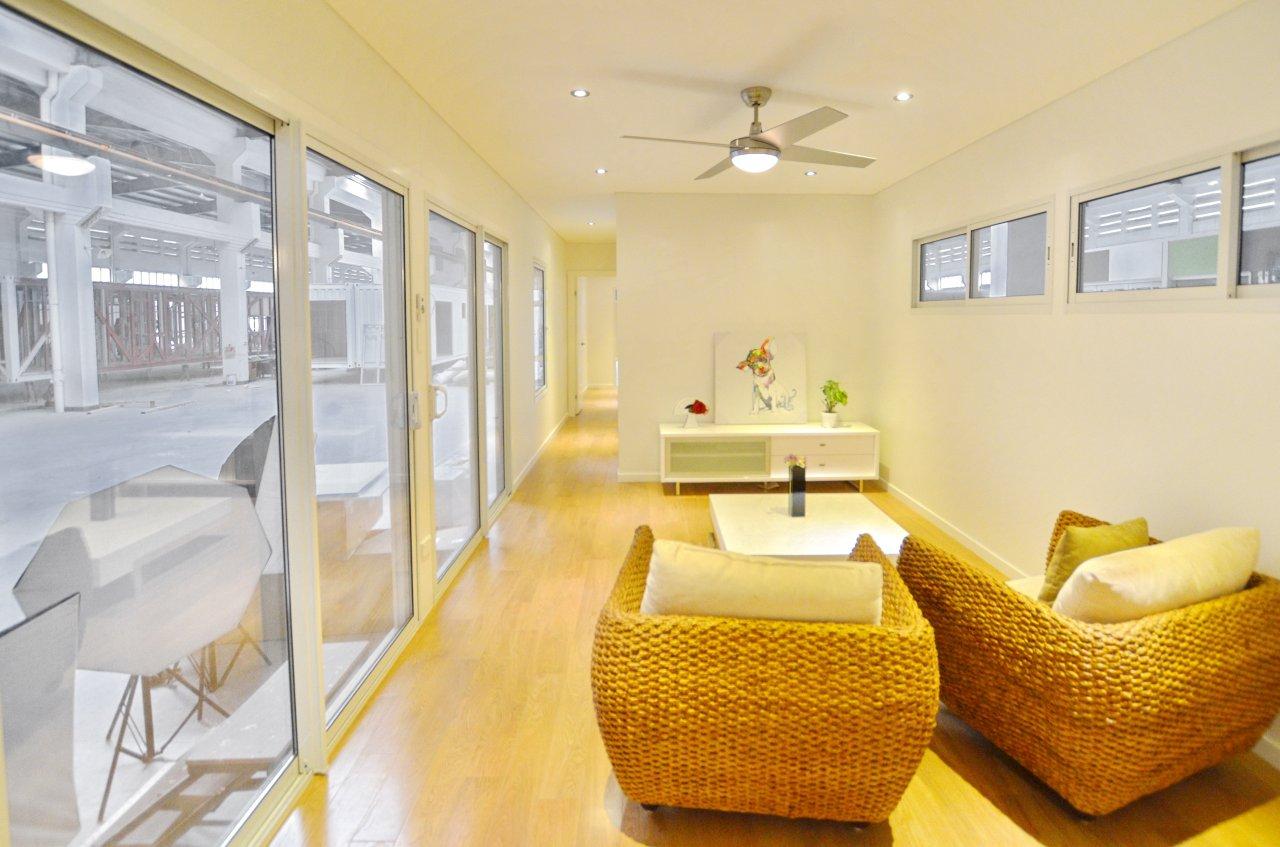 A modern living room with wicker armchairs, glass doors, and light wooden floors.