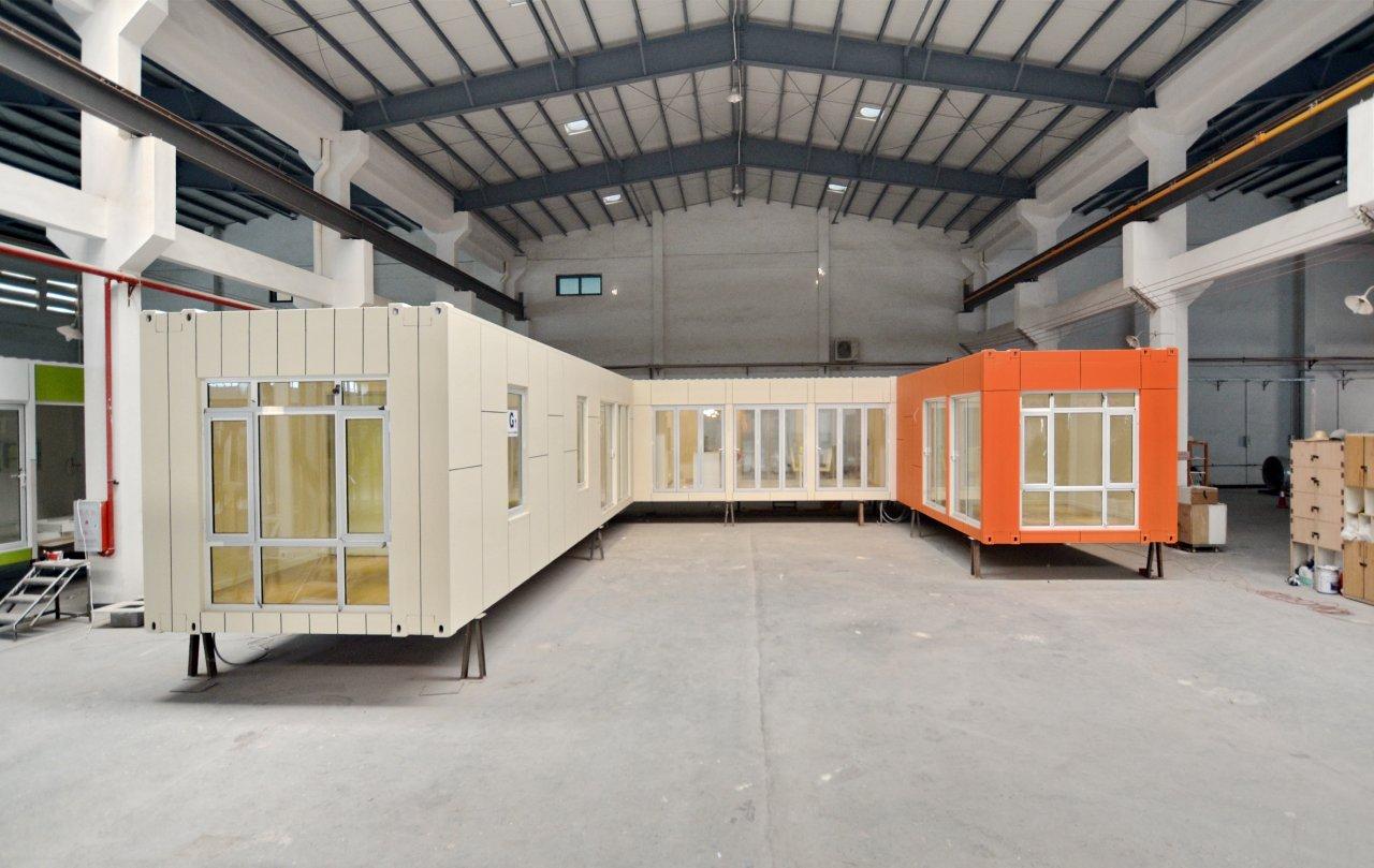 Modular buildings in an industrial warehouse. One section is orange, the rest is beige with windows.
