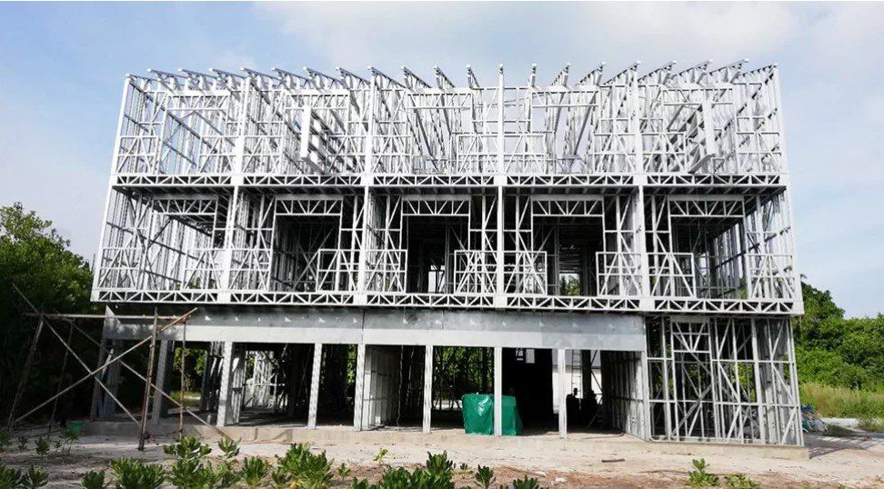 Two-story steel frame building under construction, exterior view with open windows and doors.