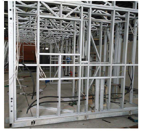 Metal framing of a building interior with wiring, conduits, and openings for doors and windows.