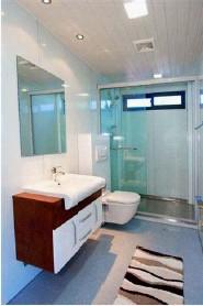 Modern bathroom with a white sink, brown cabinet, and glass shower.