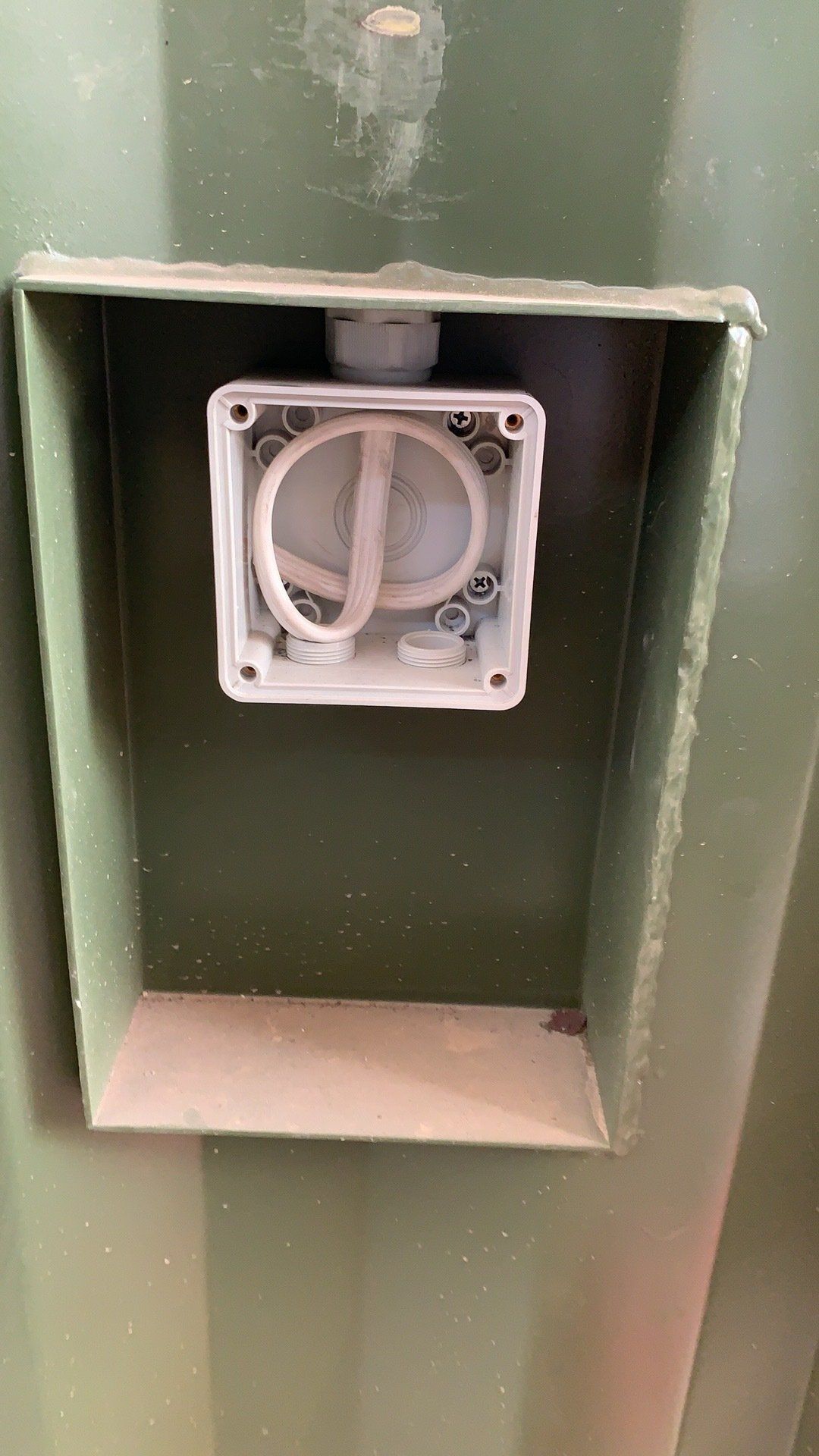 Green metal box with a white electrical junction box inside.