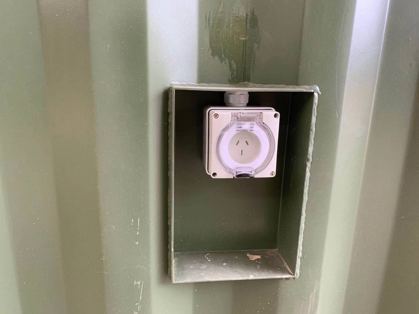 An Australian power outlet installed on a green metal container.
