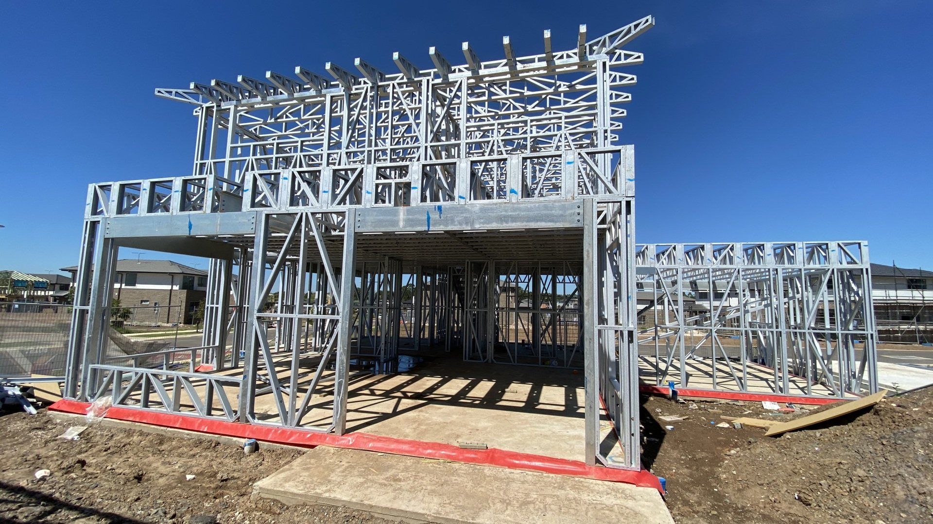 Steel frame of a house under construction; blue sky in background.