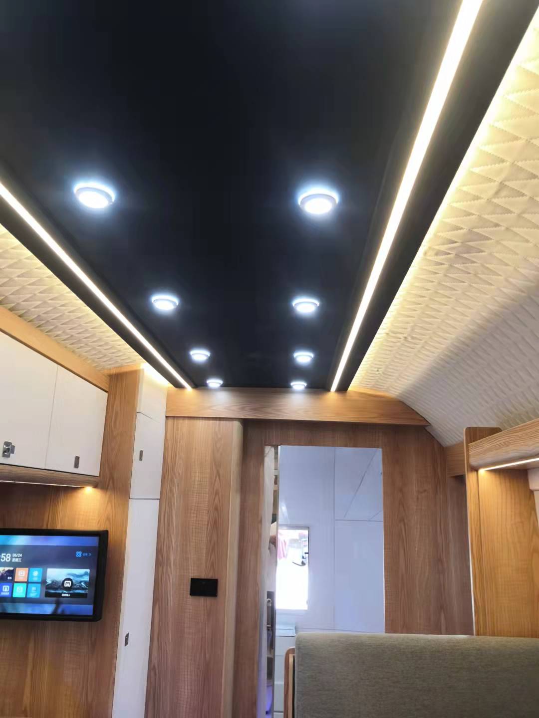 Interior view of a vehicle with a black ceiling, white and wooden walls, and recessed lighting.