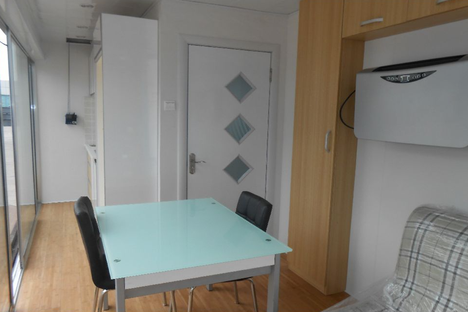 Interior of a small living space with table, chairs, door, and built-in cabinet.