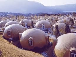 Dozens of beige, dome-shaped houses on a hillside, with mountains visible in the distance.