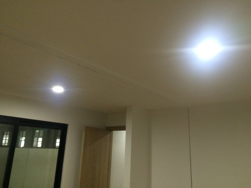 Bright ceiling lights in a room with a dark window and open doorway.