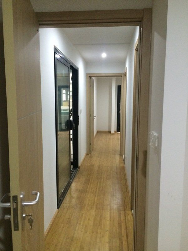 Long hallway with wood floor, white walls, and multiple doors. One door is open.