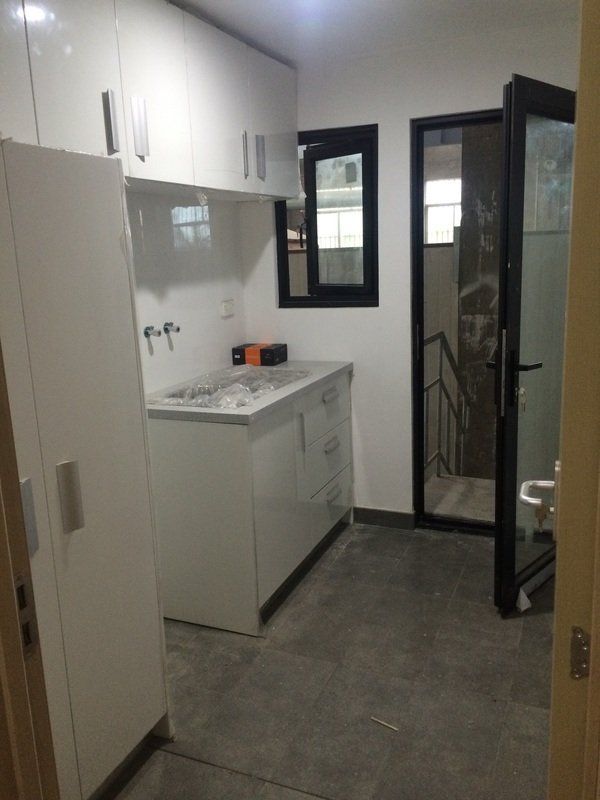White kitchen with cabinets, sink, and open door to stairs.