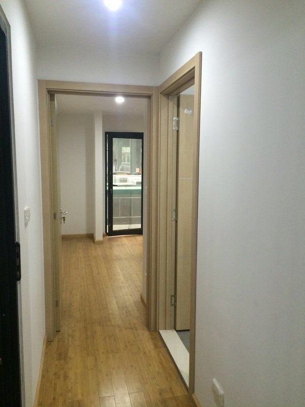 Hallway with wooden floors and three doorways. Light-colored walls and door frames.