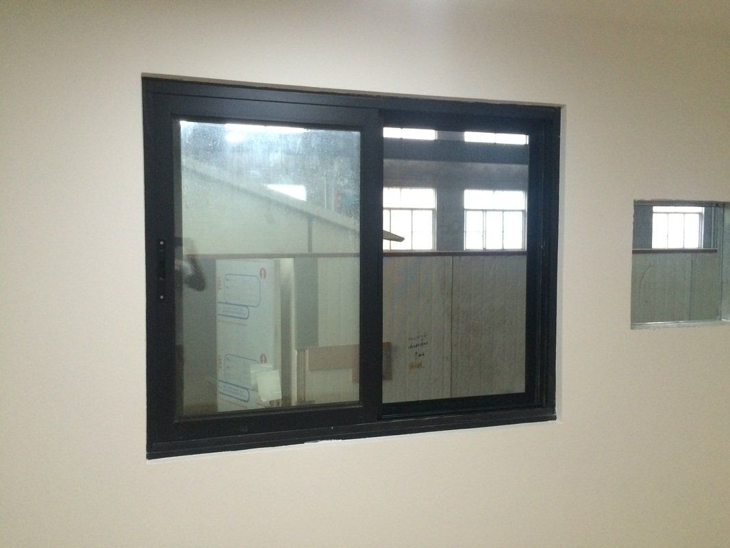Black framed sliding window on beige wall with a smaller window nearby.