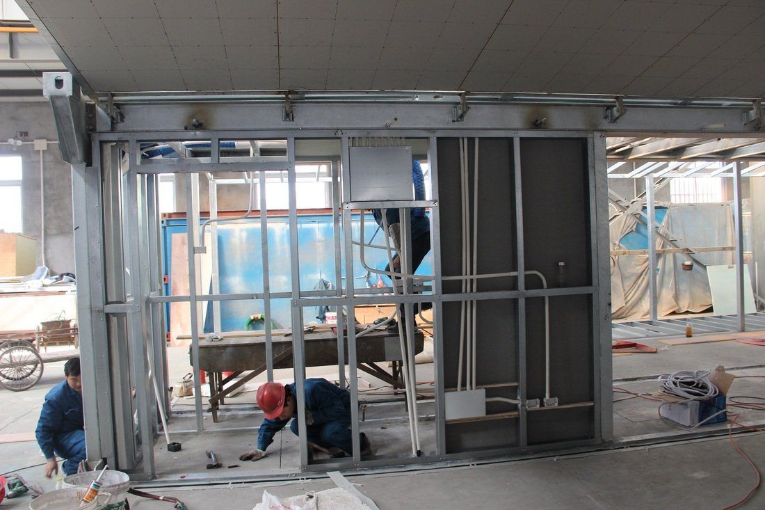 Construction workers installing metal framing for an interior wall, in a building under renovation.