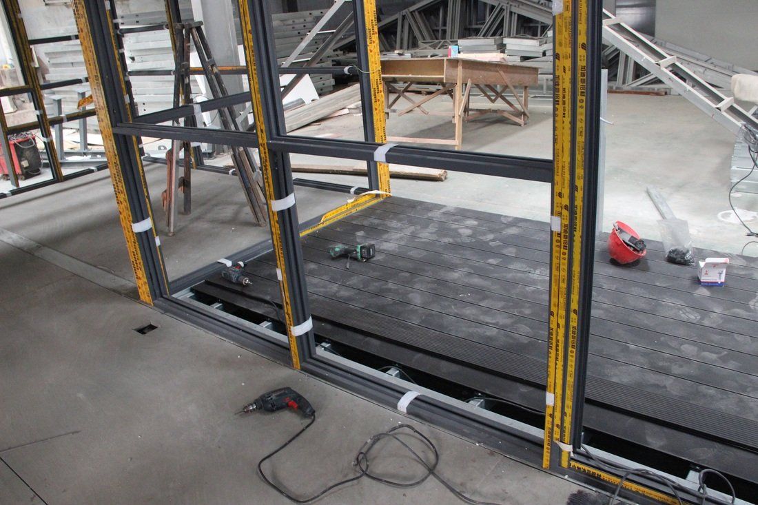 Window frames being installed indoors, with tools and materials on the floor.