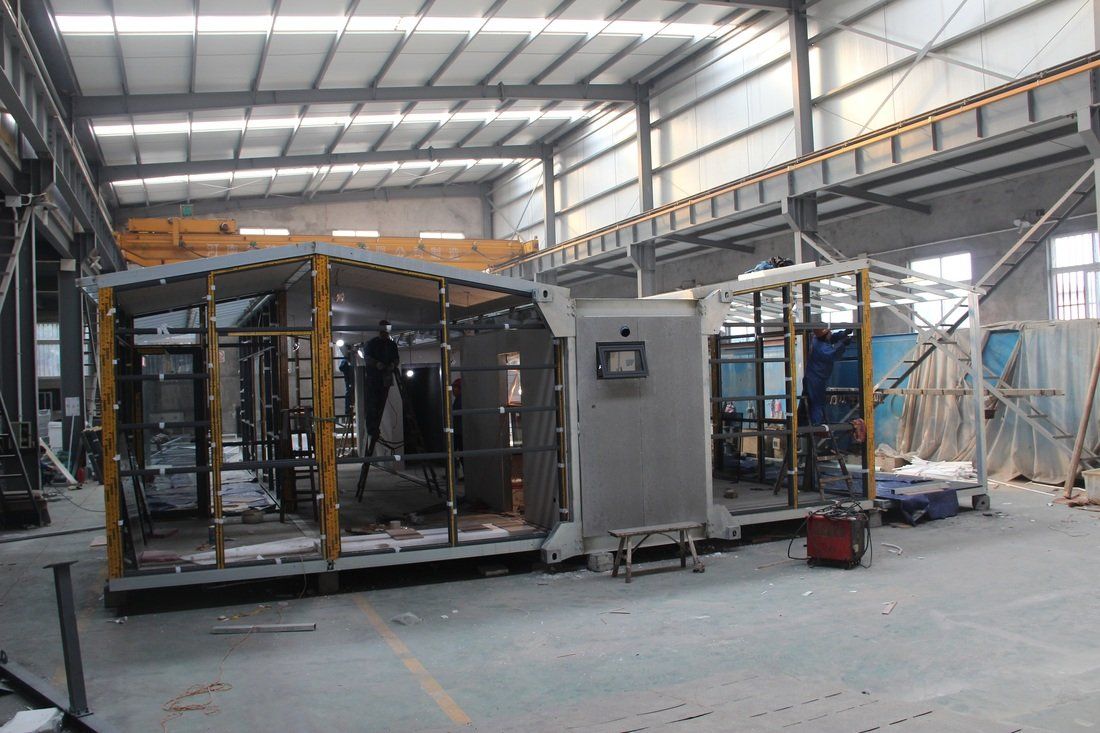 A large industrial building interior with unfinished metal frames of structures under construction.
