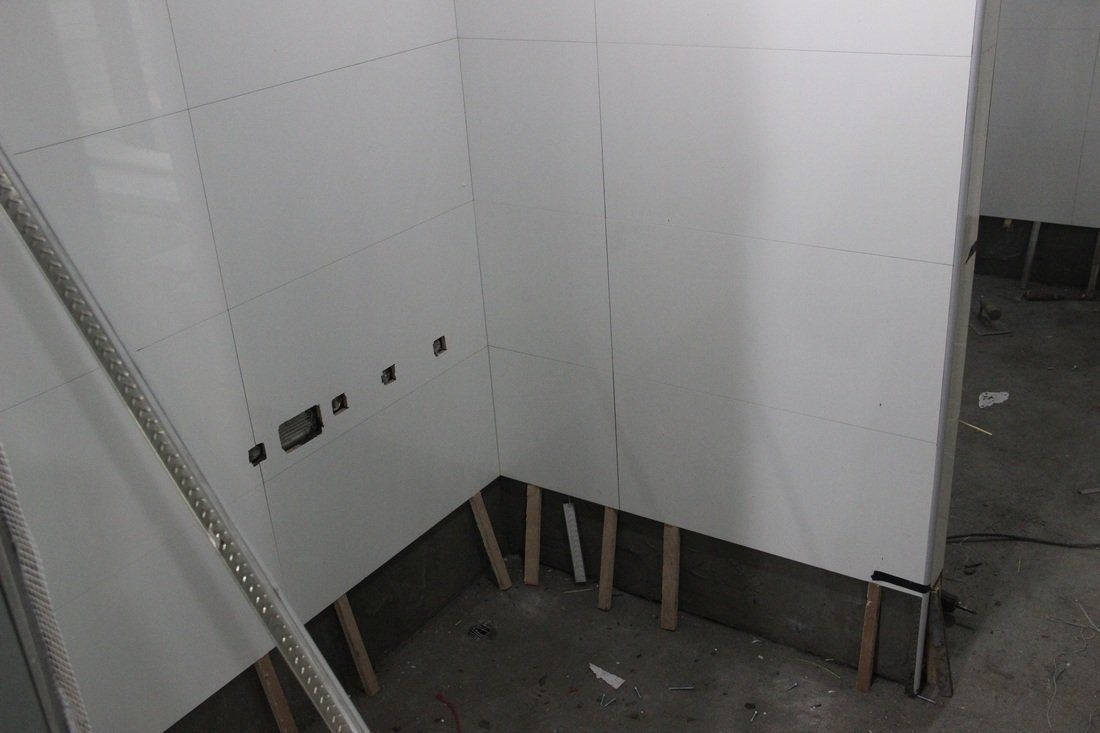White-walled room corner with vertical wooden supports at the base. Electrical outlets visible.