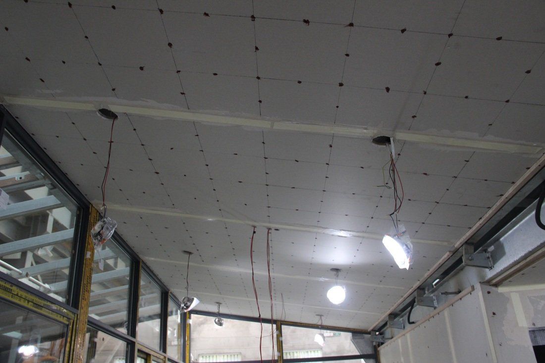 Ceiling with drywall in progress, exposed wiring, and partially installed lighting fixtures.