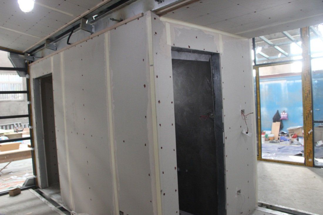 Construction site with drywall walls, doorways, and a partially visible window.
