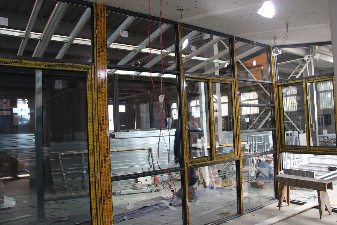 Interior construction site with glass wall partitions, yellow frames.