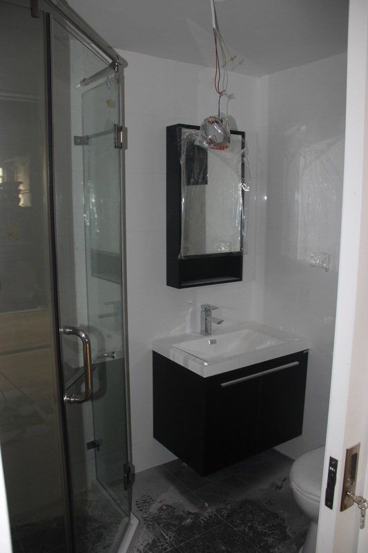 Modern bathroom with glass shower, black vanity, and hanging light fixture.
