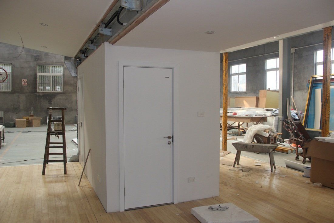 Interior room under construction, featuring a white door, light wooden floor, and partially built walls.