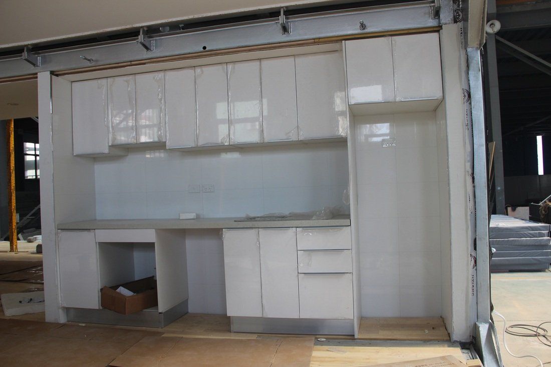 White kitchen cabinets and countertops being built in a construction zone.