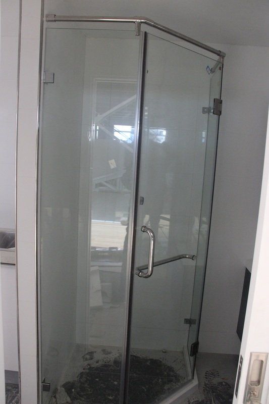 Glass shower enclosure with chrome hardware in a bathroom.