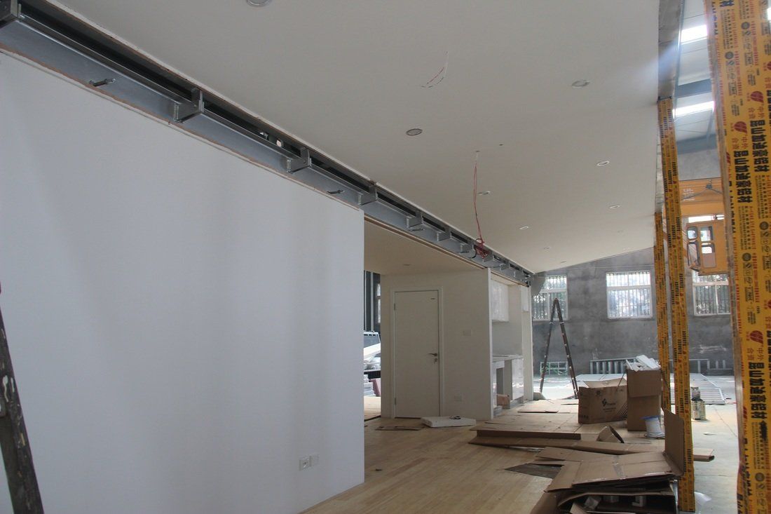 Interior under construction: white walls, exposed metal beams, and wooden flooring.