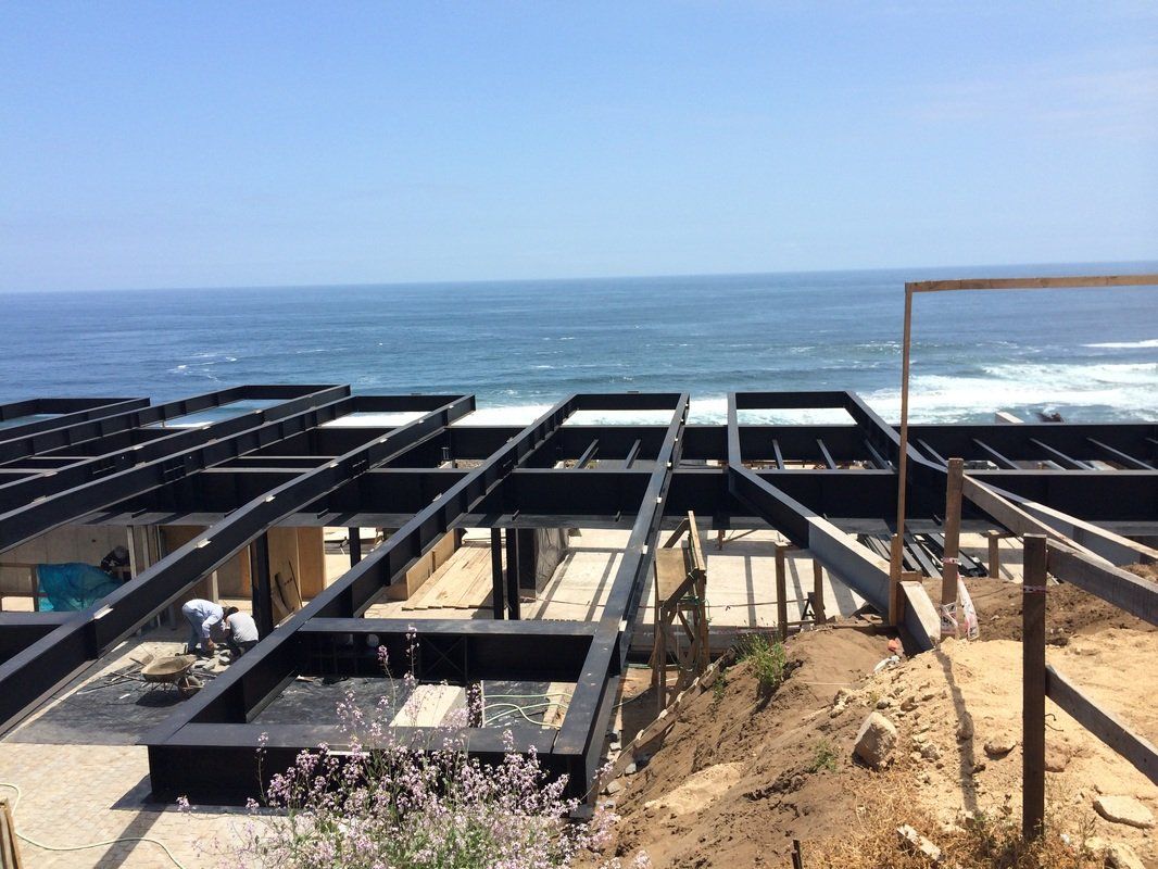 Steel framework of a building under construction on a cliff overlooking the ocean. Sunny day.