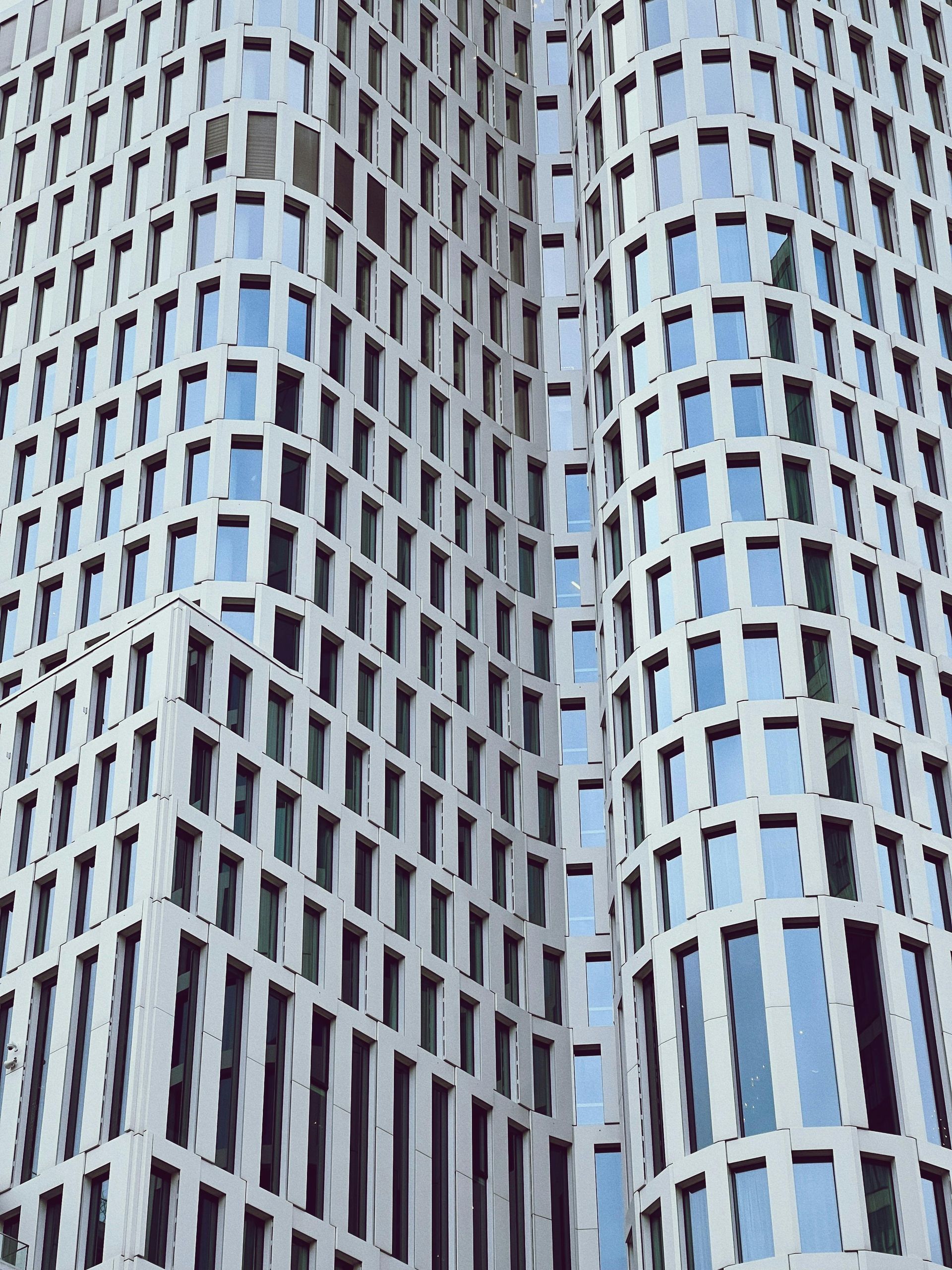 High-rise building exterior with repeating window pattern; white facade, curved sections.