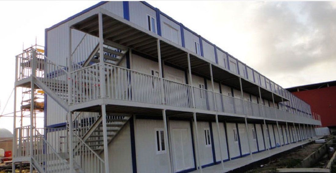 Multi-story modular building with exterior staircases, white walls, and blue trim.