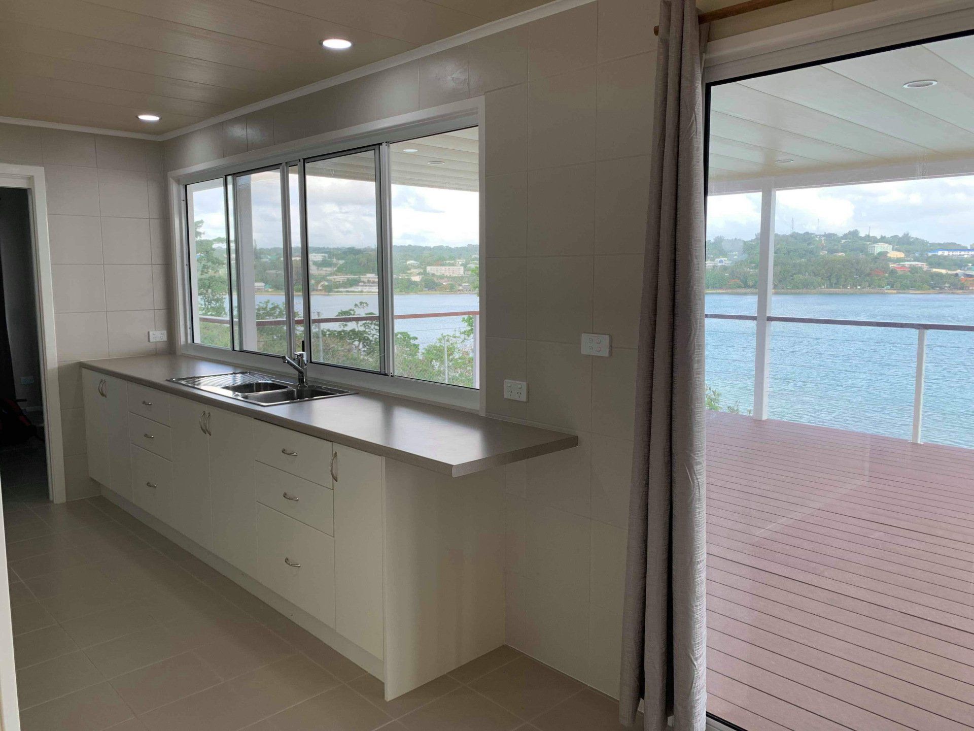 Kitchen with countertop and cabinets, large windows with water view, sliding door to deck.