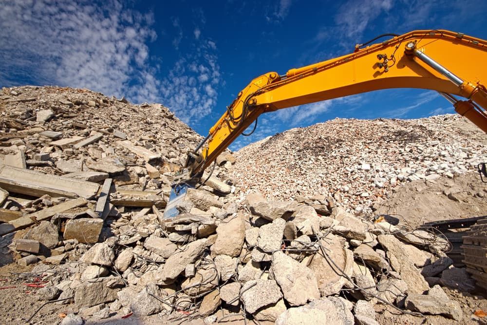 A Yellow Excavator Is Working on A Pile of Rocks — Albury Demolitions in Lavington, NSW