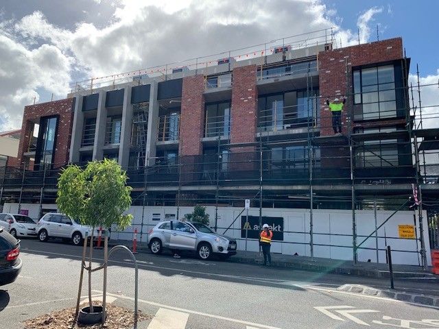 A building under construction with scaffolding around it and cars parked in front of it.