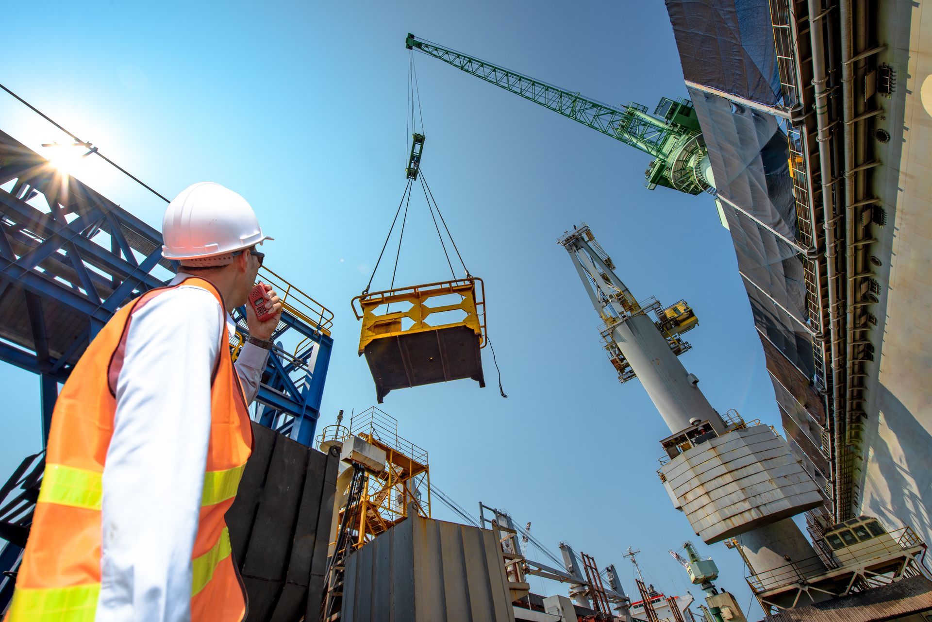 An engineer using a walkie talkie for a crane lifting safety operation in a loading dock.