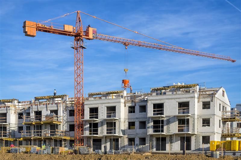 Orange tower crane at a multi-story building construction site.