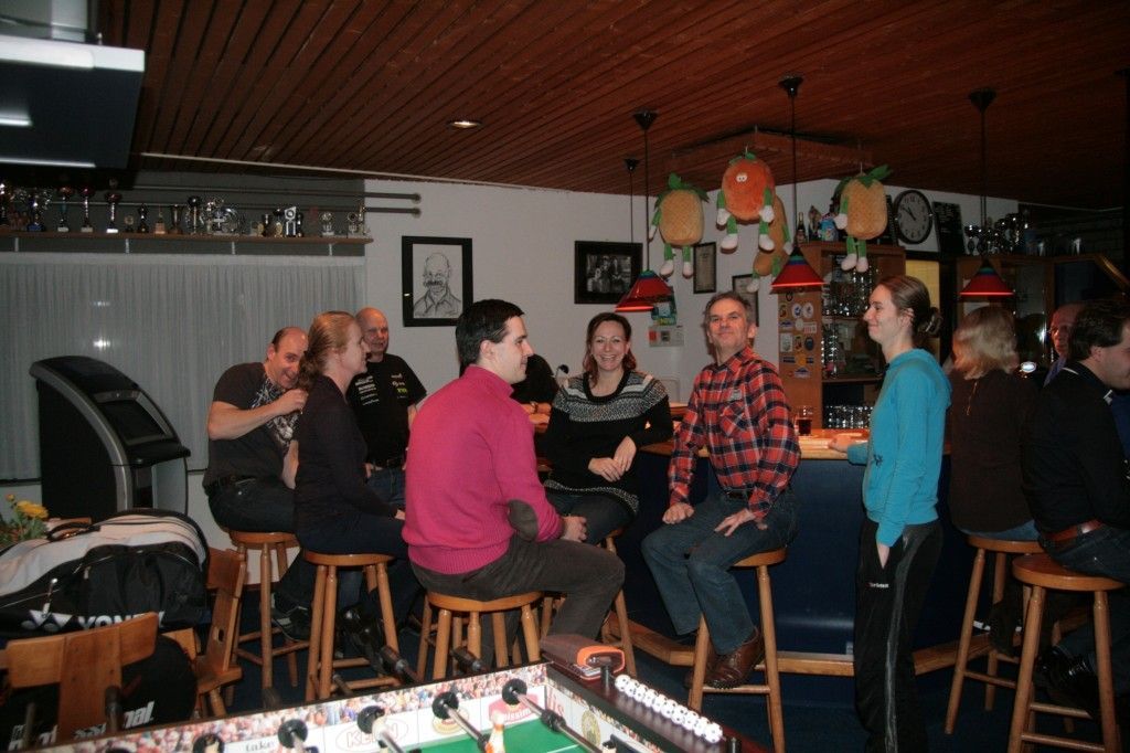 Een groep mensen die gezellig samen zijn in een schemerige bar, zittend op barkrukken aan de bar